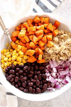 a bowl filled with beans, rice, and sweet potato salad next to a fork