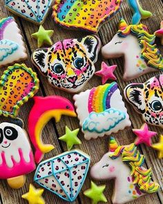 decorated cookies with different designs and colors on a wooden surface, including unicorns, cats, stars, and clouds