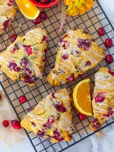 orange cranberry scones on a cooling rack next to fresh fruit and flowers