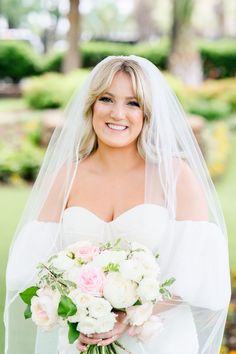 a woman in a wedding dress is holding a bouquet and posing for the camera with her veil over her head