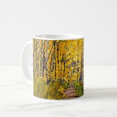 a coffee mug with an image of a path in the woods surrounded by yellow leaves