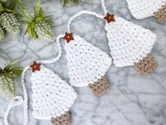 three crocheted christmas tree ornaments on a marble surface