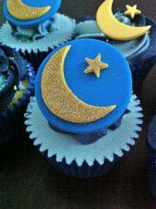 cupcakes with blue frosting and gold stars on them, sitting on a table