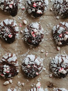 chocolate cookies covered in candy canes and powdered sugar on top of parchment paper