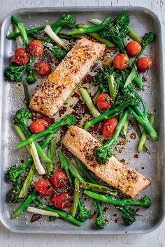 salmon, broccoli and tomatoes on a tray with seasoning sprinkles