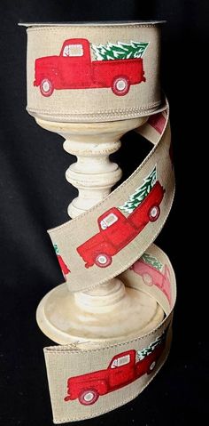 a red truck with a christmas tree on it is sitting next to a roll of ribbon