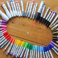 many different colored crayons are arranged in the shape of a circle on a wooden table