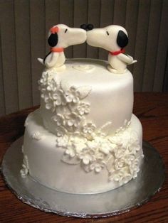 a wedding cake with two dogs on top and white frosting flowers around the edges