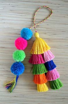 multicolored tasselled pom - poms hanging from string on wooden surface