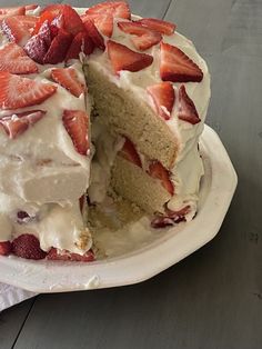 a cake with white frosting and sliced strawberries on top is sitting on a plate