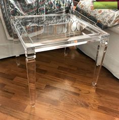 a clear glass coffee table sitting on top of a hard wood floor next to a couch