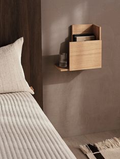 a small wooden shelf on the wall above a bed