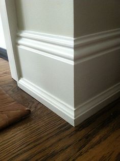 the corner of a room with a brown leather chair and wooden floor next to it