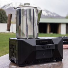 a coffee pot sitting on top of a black stove next to a metal container with a wooden handle