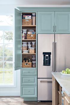 a kitchen with blue cabinets and white counter tops, an open pantry door is shown