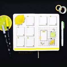 an open planner with lemons, scissors and tape next to it on a black surface