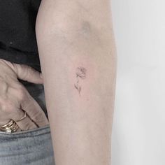 a person with a small flower tattoo on their arm