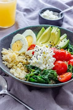 a salad with eggs, tomatoes, spinach and avocado in a bowl