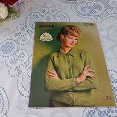 a woman's sweater pattern on a tablecloth with flowers in the back ground