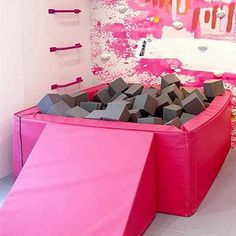 a room with pink and grey furniture on the floor in front of a wall decorated with art