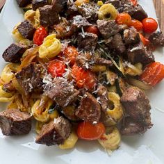 a white plate topped with pasta and meat