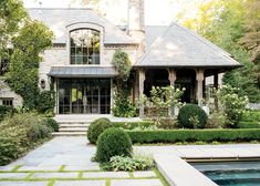 a house with a pool in front of it and lots of greenery on the side