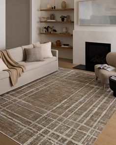 a living room with a couch, chair and rug on the floor in front of a fireplace