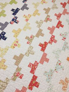 a close up of a quilt on a bed with many different colors and shapes in it