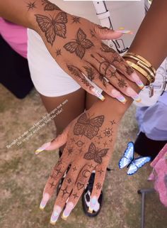 two women's hands with tattoos on them, one has butterflies and the other has stars