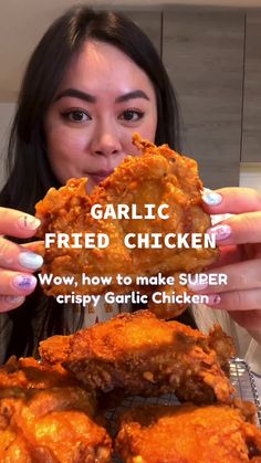 a woman holding up some fried chicken in front of her face and the words garlic fried chicken wow, how to make super crispy garlic chicken