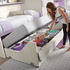 a woman is opening the drawers of a bed in a room with purple walls and carpet