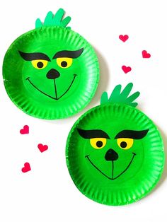 two green paper plates with faces on them and hearts floating in the air behind them