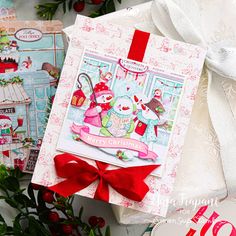 two christmas cards with red bows on them next to some flowers and other holiday decorations