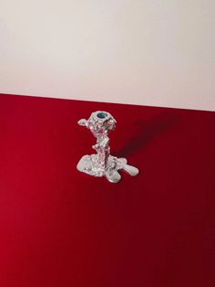 a silver figurine sitting on top of a red table next to a white wall