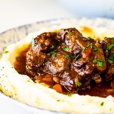 a plate topped with mashed potatoes and meat covered in gravy, garnished with parsley