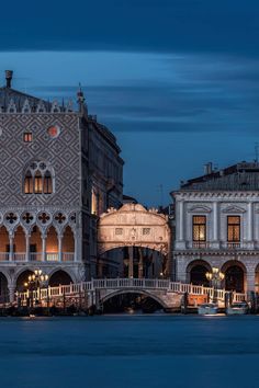 the buildings are lit up at night on the water's edge in venice, italy