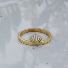 a gold ring sitting on top of a white surface with a diamond in the middle