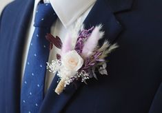 a boutonniere with feathers and flowers is worn on a man's suit