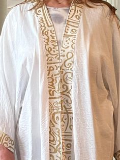 Open long white Arabic calligraphy kaftan with gold embroidery. Free size. Linen. White Kaftan With Gold Embroidery For Eid, White Gold Embroidered Kaftan For Eid, Elegant White Kaftan With Gold Embroidery, White Long Sleeve Kaftan With Gold Embroidery, Elegant White Kimono For Eid, Traditional White Thobe With Long Sleeves, Traditional White Long Sleeve Thobe, Traditional Gold Tunic Kaftan, Traditional White Tunic Kaftan