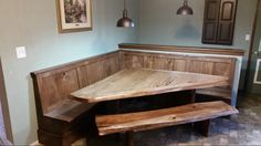 a wooden table and bench in the corner of a room with two lights hanging above it