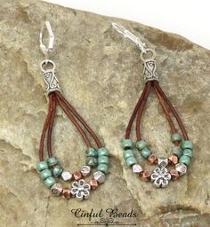 the earrings are made with beads and leather cord, on top of a stone slab