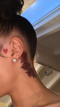 a woman with tattoos on her neck and behind her ear is looking into the distance