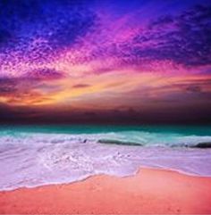 an ocean beach with waves coming in to shore and colorful clouds above the water at sunset