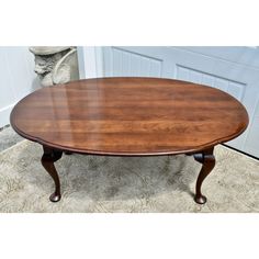 an oval wooden table sitting on top of a carpeted floor next to a white door