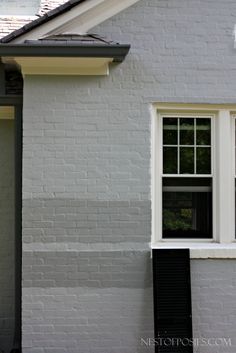 a cat sitting on the ledge of a window sill in front of a house