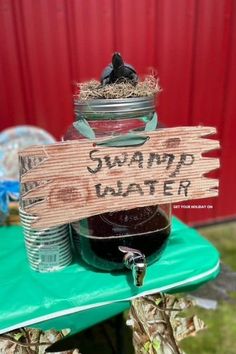 a wooden sign sitting on top of a green table covered in jars filled with food