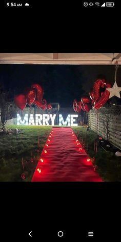 a long red carpeted path leading to a large sign that says marry me on it