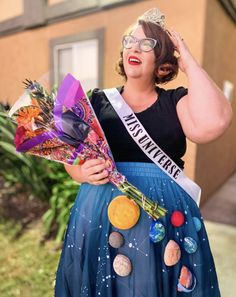 a woman in a blue skirt holding flowers and wearing a tiara with planets on it