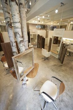 an empty room with chairs and mirrors on the floor in front of it, surrounded by birch trees