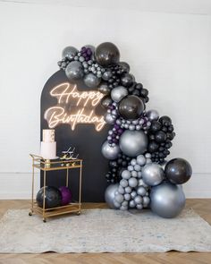 a birthday cake and balloons on a table with a sign in the background that says happy birthday